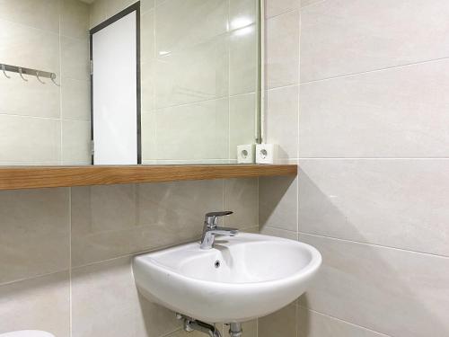 a bathroom with a sink and a mirror at Good and Homey 1BR Apartment at Mustika Golf Residence By Travelio in Cikarang