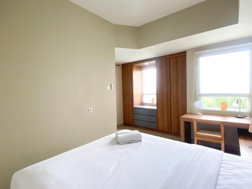 a bedroom with a white bed and a desk and a window at Good and Homey 1BR Apartment at Mustika Golf Residence By Travelio in Cikarang