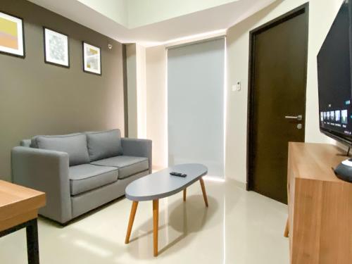 a living room with a couch and a table at Good and Homey 1BR Apartment at Mustika Golf Residence By Travelio in Cikarang