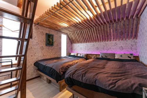 two beds in a room with a brick wall at Grand Piano & Shinjuku 5min walk from station in Tokyo