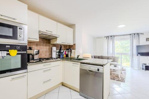 une cuisine avec des armoires blanches et un four à plaques de cuisson dans l'établissement L'Escapade du Lac - Proche du Lac Léman, à Évian-les-Bains