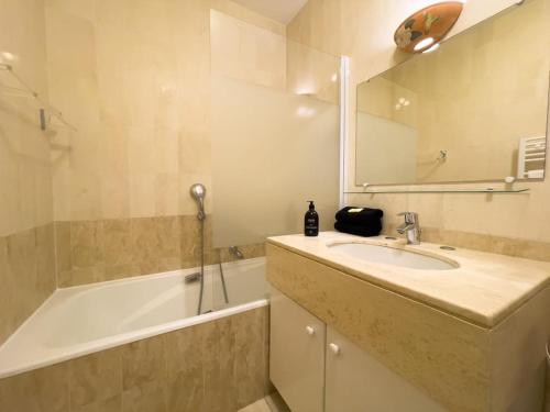 une salle de bain avec un lavabo, une baignoire et un miroir dans l'établissement Rénové, grande terrasse, piscine, au calme absolu, à Cannes