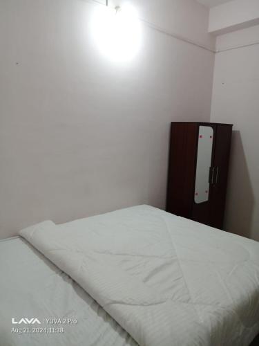 a bedroom with a white bed with a wooden headboard at Shivam Guest House Near GNRC and Down Town Hospital in Dispur
