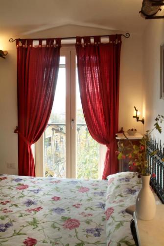 a bedroom with a bed and a window with red curtains at Hotel Villa Rizzo Resort and Spa in San Cipriano Picentino