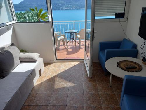 a living room with a couch and a table and a balcony at Bay View Apartment in Herceg-Novi