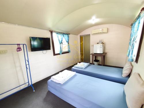 two beds in a small room with a tv at Goldengold (Khaoyai) Resort & Spa in Mu Si