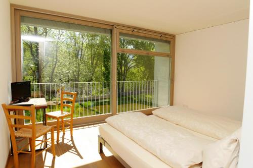 a bedroom with a bed and a desk and a window at Casa Martinelli, Boutique-Hotel in Maggia
