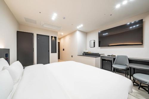 a bedroom with a white bed and a table and chairs at Mokpo Brown Dot Hotel Namak in Mokpo