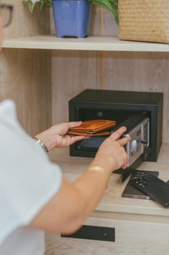 a woman is putting food in a toaster oven at Botan Boutique Hotel in Patong Beach