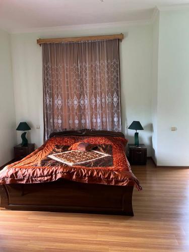 a bedroom with a bed with a red comforter and a window at GuestHouse Tekhura in Martvili