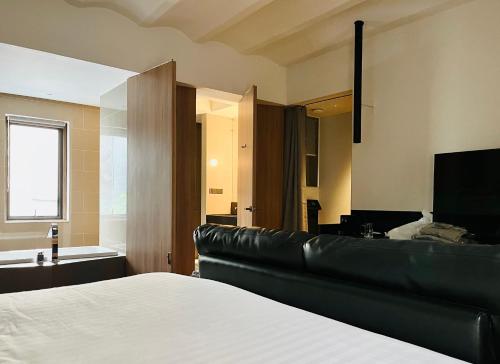 a bedroom with a black leather couch and a television at Hotel Noir in Chiang Mai