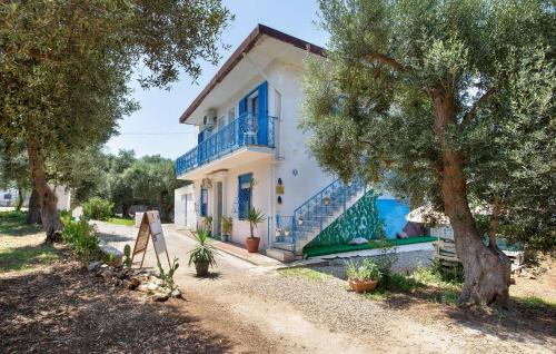 a white house with blue windows and stairs and trees at Panoramic House in Palmi