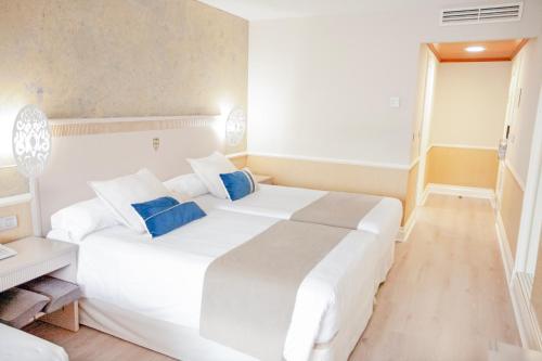 a white bedroom with a large white bed with blue pillows at Hotel Alfonso VIII in Soria