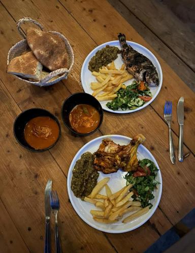 four plates of food on a wooden table at Ghar El Melh Outdoors in Raʼs al Jabal