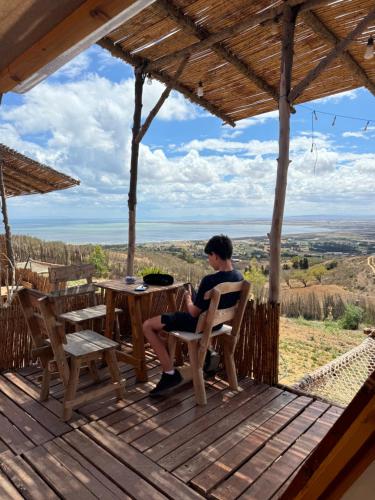 a man sitting in a chair on a wooden deck at Ghar El Melh Outdoors in Raʼs al Jabal