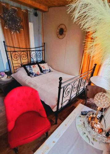 a bedroom with a bed and a red chair at DAGNA summer house in Šunupis