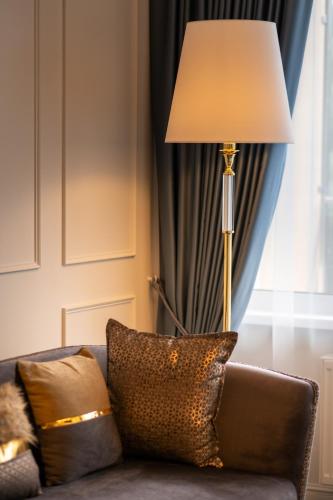 a lamp sitting next to a couch with a pillow at Gradiali Wellness and SPA in Palanga