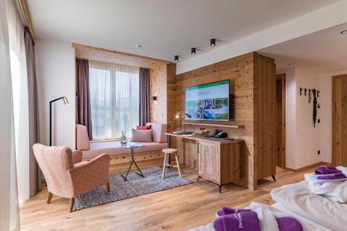 a bedroom with a desk and a couch and a television at Hotel Penzinghof in Oberndorf in Tirol