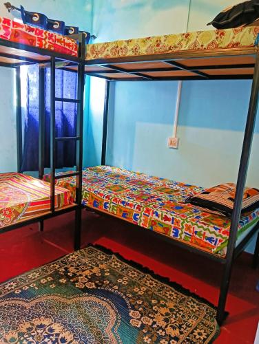 two bunk beds in a room with a rug at Beach Clan Dorms in Alleppey
