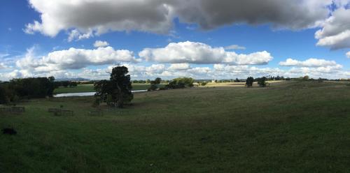 a large open field with trees and a river at A rural retreat with space and light in Birlingham