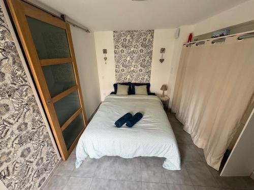 Cette petite chambre comprend un lit blanc avec des oreillers bleus. dans l'établissement Charmant Appartement dans village typique du Sud, à Lespignan