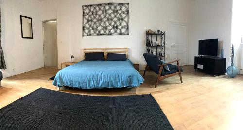 a bedroom with a bed and a chair and a television at Manoir Les Vieilles Aires in Montauban-de-Bretagne