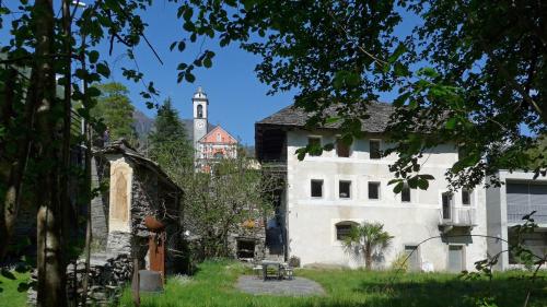 a large white building with a church in the background at Casa Martinelli, Boutique-Hotel in Maggia