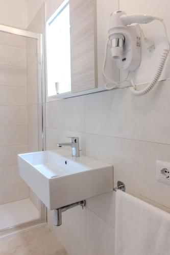 a white bathroom with a sink and a mirror at Agriturismo Brancalino in Magliano in Toscana