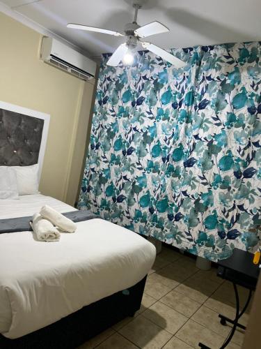 a bedroom with two beds and a floral wallpaper at Flamingo B&B in Richards Bay