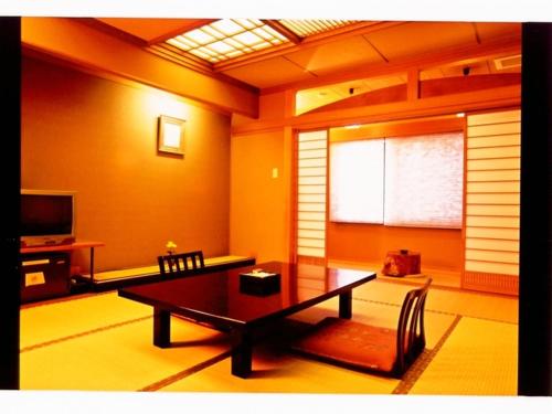 a living room with a table and a television at Yunokura Tsuruya in Makago