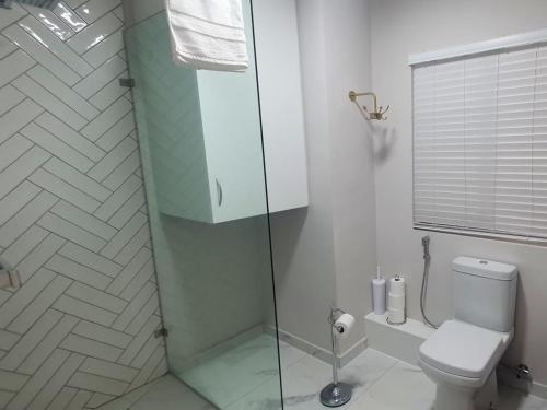 a bathroom with a toilet and a glass shower at Bloubergstrand Beachfront Apartment Witsand 101 Tablemountain and ocean views in Cape Town