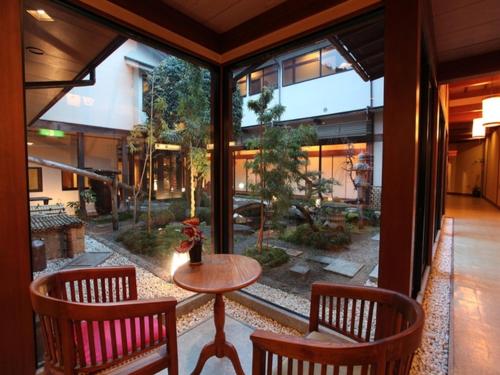 a room with a table and chairs and a large window at Yunokura Tsuruya in Makago