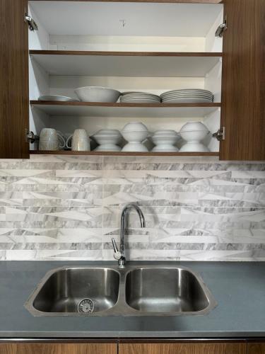 a kitchen sink with plates and bowls on a shelf at Luxury Furnished Appartments in Abidjan