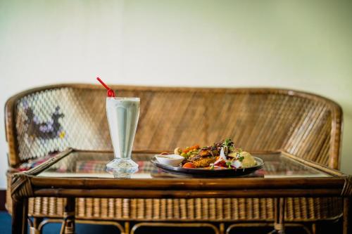 a glass table with a plate of food and a drink at Rest Up Kathmandu Hostel in Kathmandu