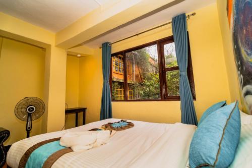 a bedroom with a bed with blue curtains and a window at Rest Up Kathmandu Hostel in Kathmandu