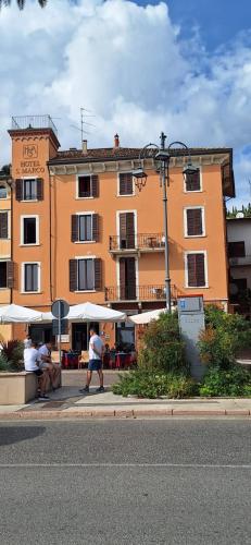 a large orange building with people walking in front of it at Hotel & Restaurant San Marco AB in Toscolano Maderno