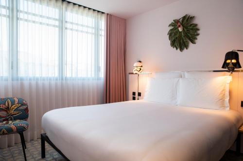 a bedroom with a large white bed and a window at Mama Shelter Lisboa in Lisbon
