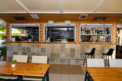 a restaurant with tables and chairs and a bar at Esperides Beach Hotel Apartments in Stalos