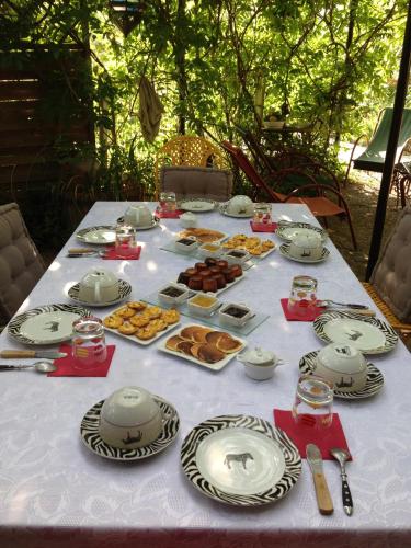 une table avec un tissu de table blanc et de la nourriture dans l'établissement Les Jardins du Rebaut, à Béziers
