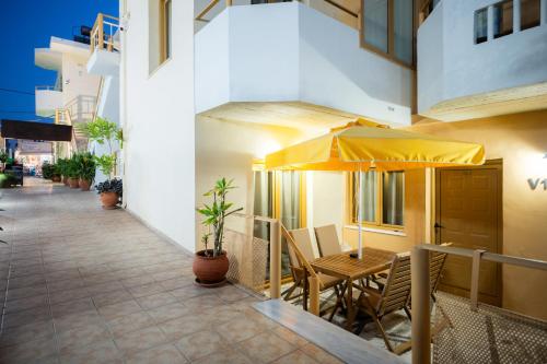 a patio with a table and an umbrella at Esperides Beach Hotel Apartments in Stalos