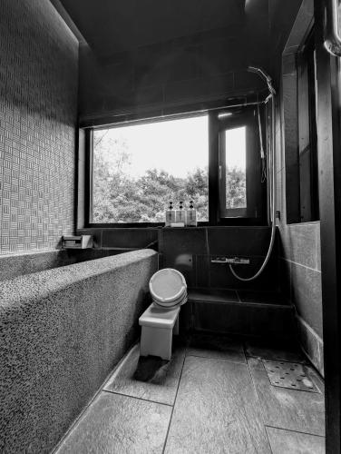 a bathroom with a toilet and a tub and a window at Ryoso Yufuin Yamadaya in Yufuin