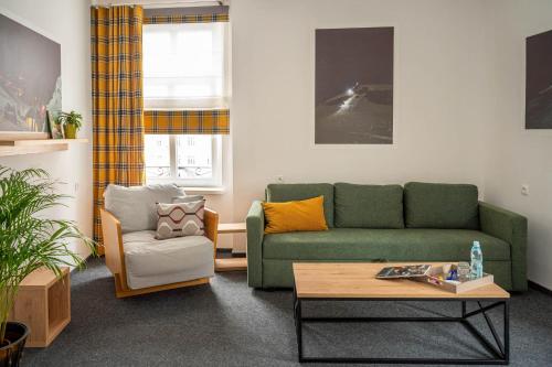 a living room with a green couch and a chair at Apartamenty na Starówce - 3 piętro z widokiem na Ratusz, Rynek Główny i Centrum in Kalisz