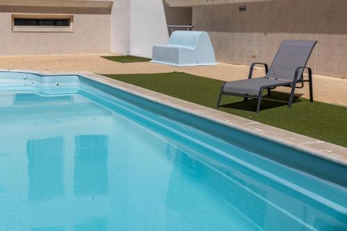 a swimming pool with a chair and a table and a chair at Lua do Mar - T2 - Piscina - Fte ao Mar- Central in Nazaré