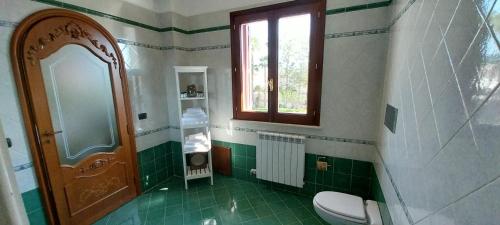 a green and white bathroom with a toilet and a window at Villa Giulia in Siracusa