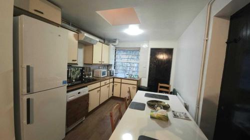 a small kitchen with a white refrigerator and a table at London Stockwell Station Apartment in London