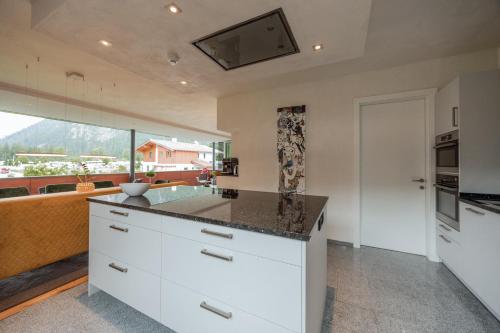 a kitchen with white cabinets and a large window at Ferienwohnungen Karlingerhof am See in Achenkirch