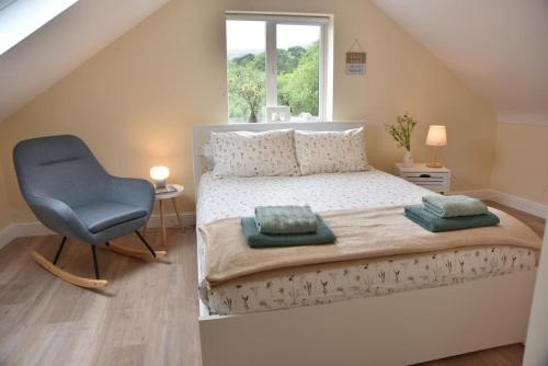 um quarto com uma cama e uma cadeira azul em Mountain View Cottage em Cloontyprughlish
