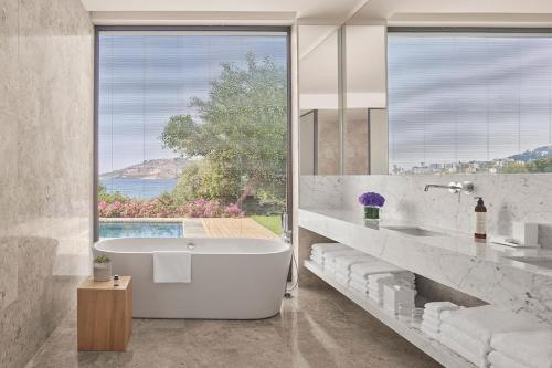 a bathroom with a tub and a large window at The Bodrum EDITION in Yalıkavak