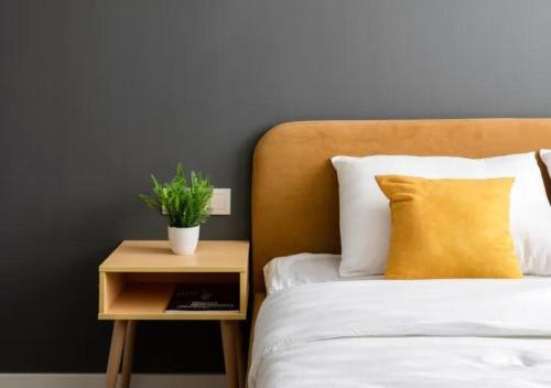 a bed with a nightstand with a plant on it at Modern апарт-отель, напротив Ботанического Сада in Astana