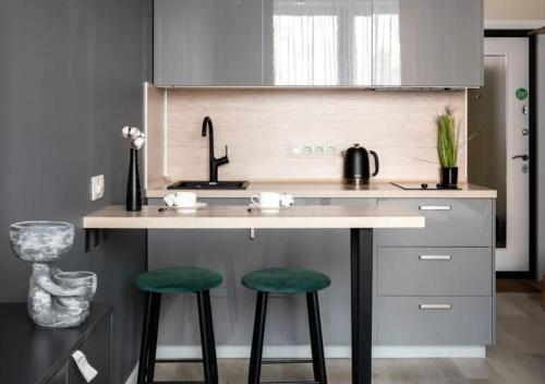 a kitchen with a counter with two green bar stools at Modern апарт-отель, напротив Ботанического Сада in Astana